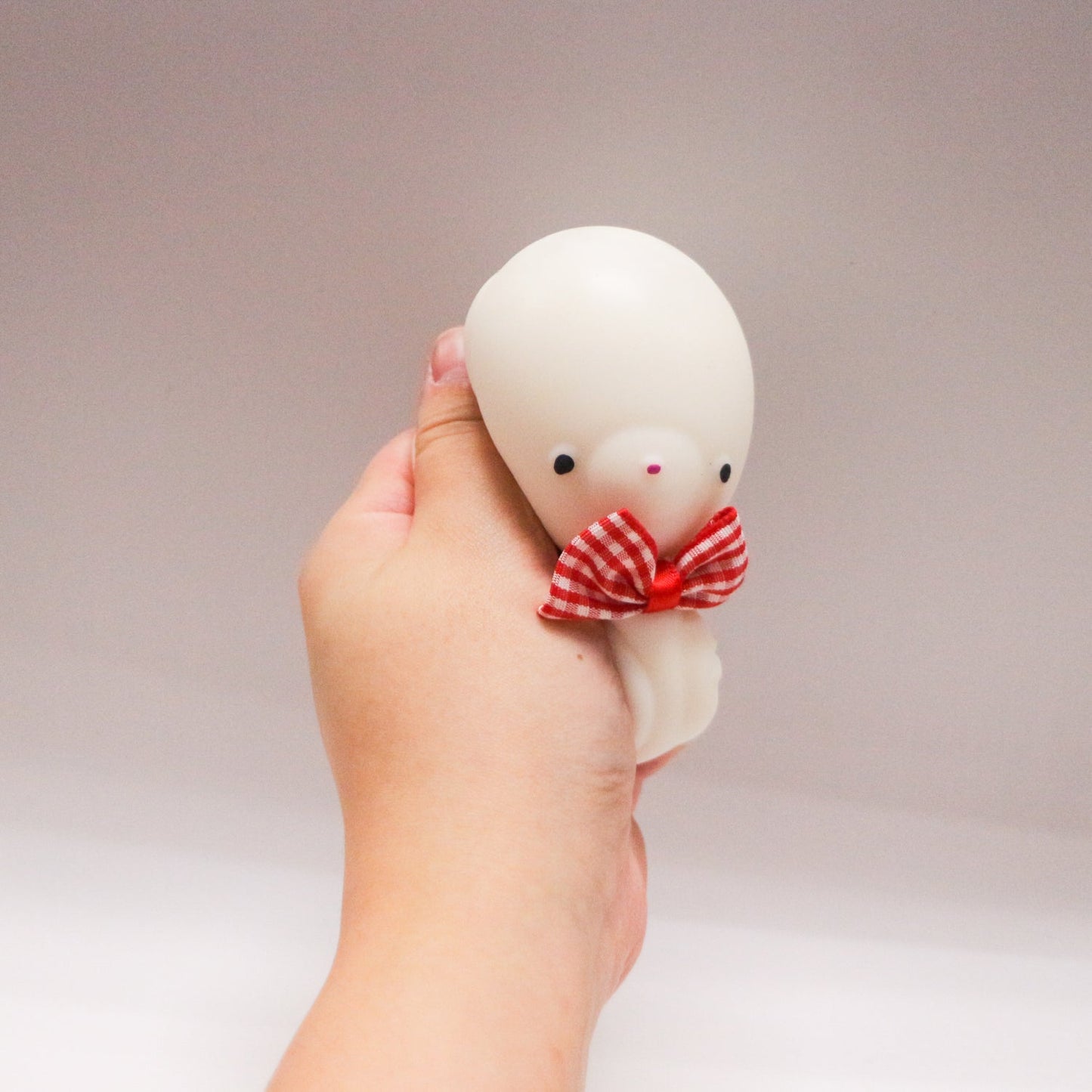 White BowBear squishy toy being squeezed by hand