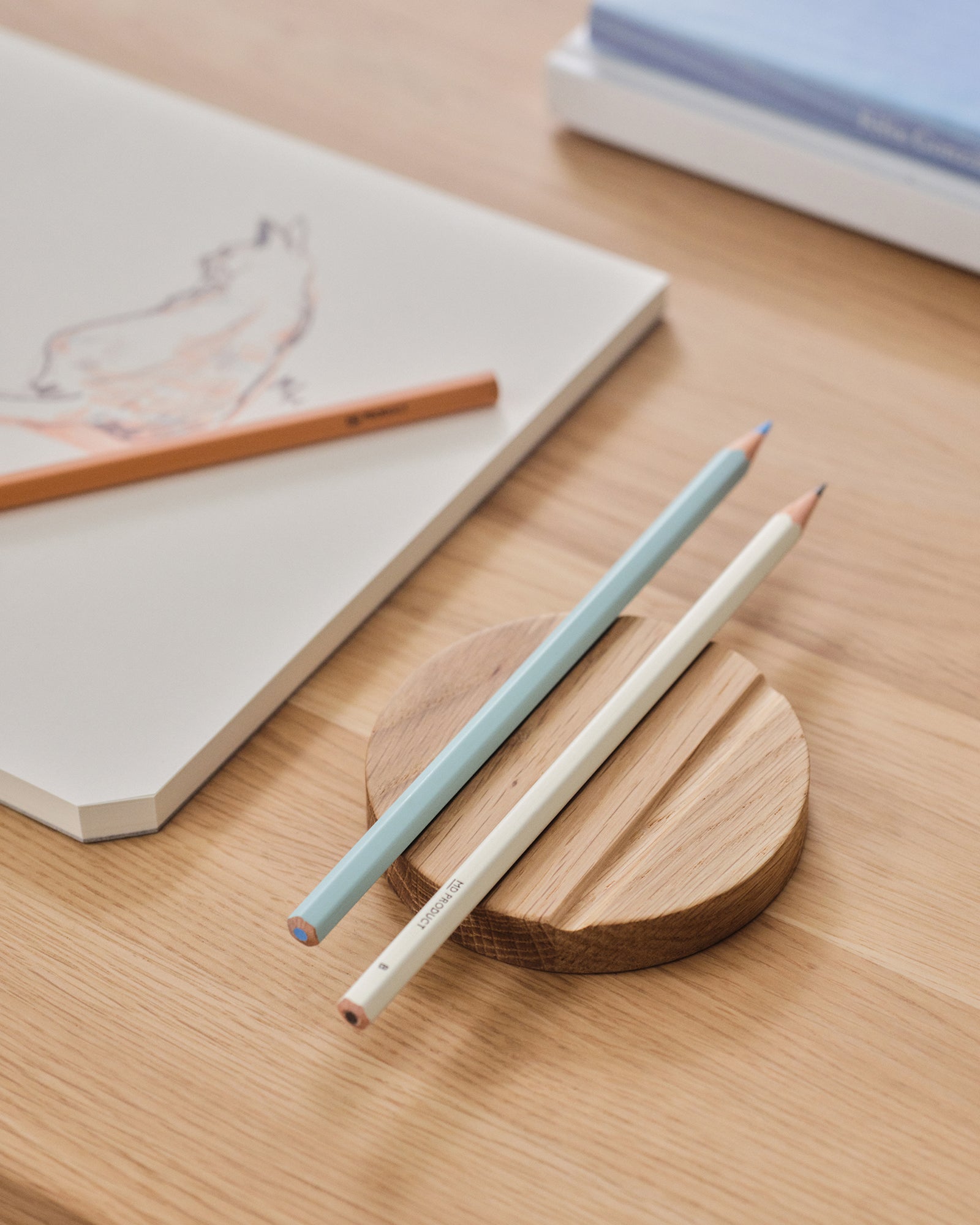 MD Pencil B and colored pencil beside a sketchbook on a desk